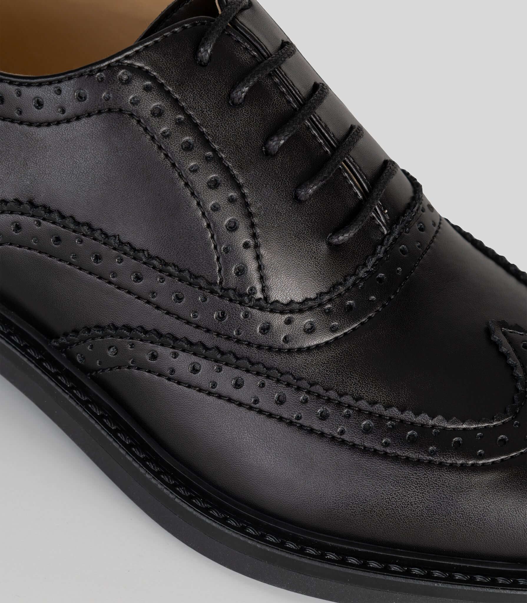 Vegan Oxford Brogue - Woman close-up showing broguing details and sleek black finish.