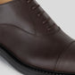 Vegan Oxford - Woman close-up of lace-up brown shoe showcasing Blake Construction details.