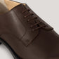 Vegan Derby - Woman close-up showing an elegant brown leather shoe with open lacing system for versatile occasions.