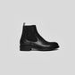 Vegan Chelsea boots - Woman in black leather with elastic side panels, showcasing elegance and sustainability.